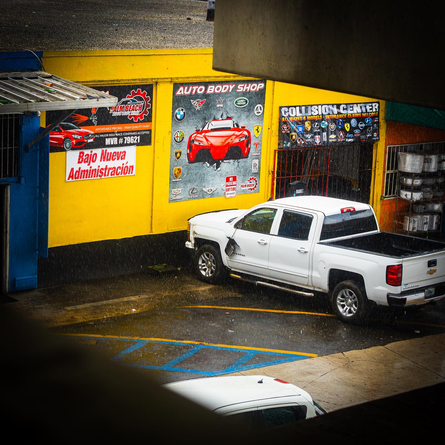 Palm Beach Auto Body Shop storefront in the rain